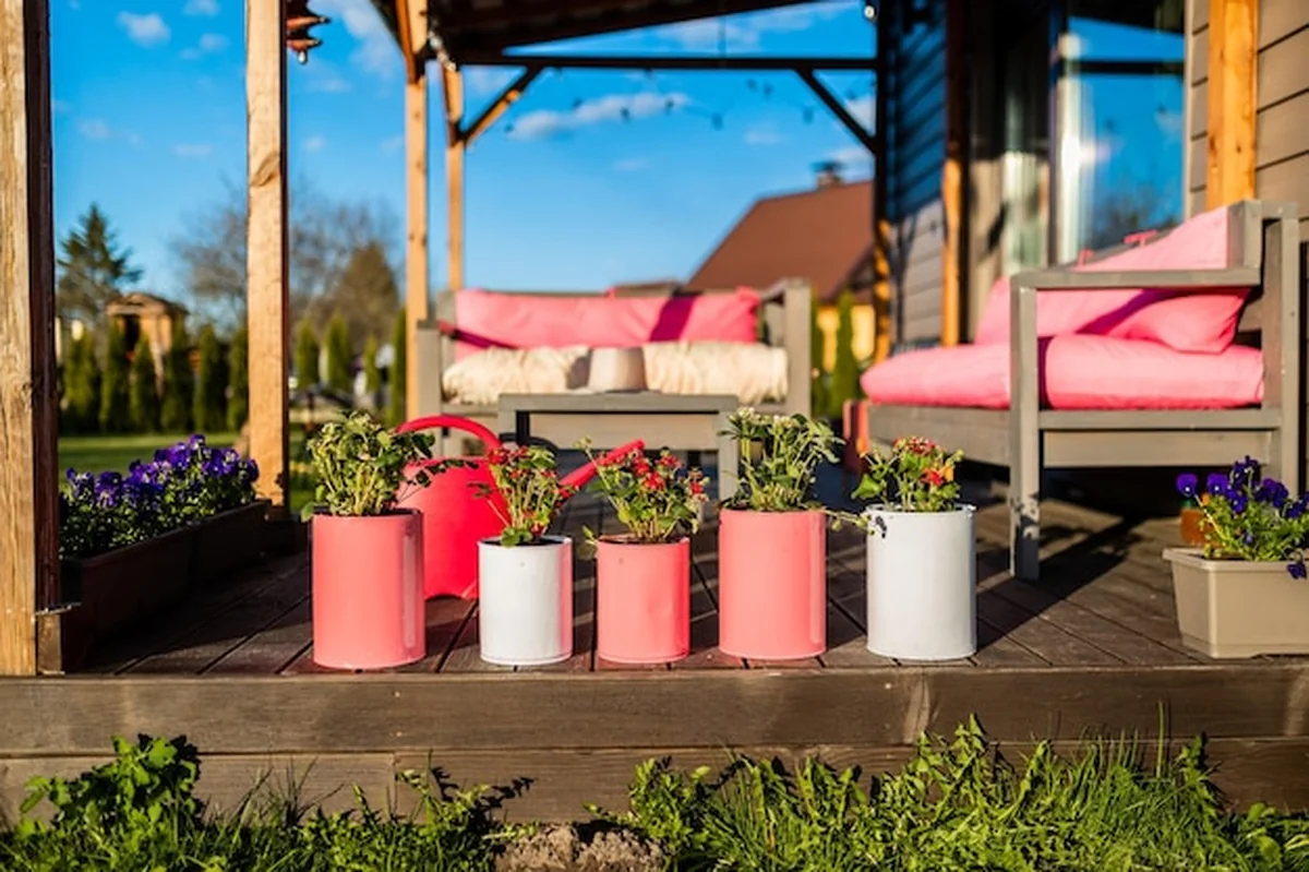 Kwiaty i truskawki w kolorowych puszkach na drewnianym tarasie domu