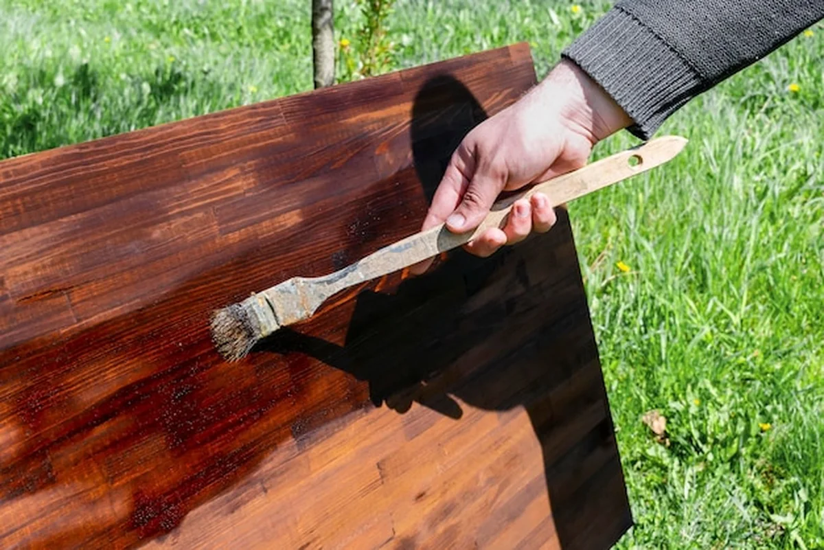 Mężczyzna maluje drewno farbą olejną na stole