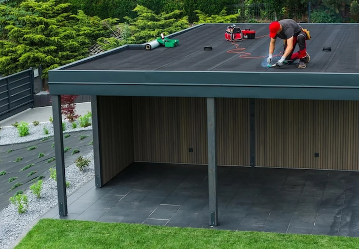 Robotnik budowlany instaluje dach na budynku mieszkalnym w ogrodzonej działce