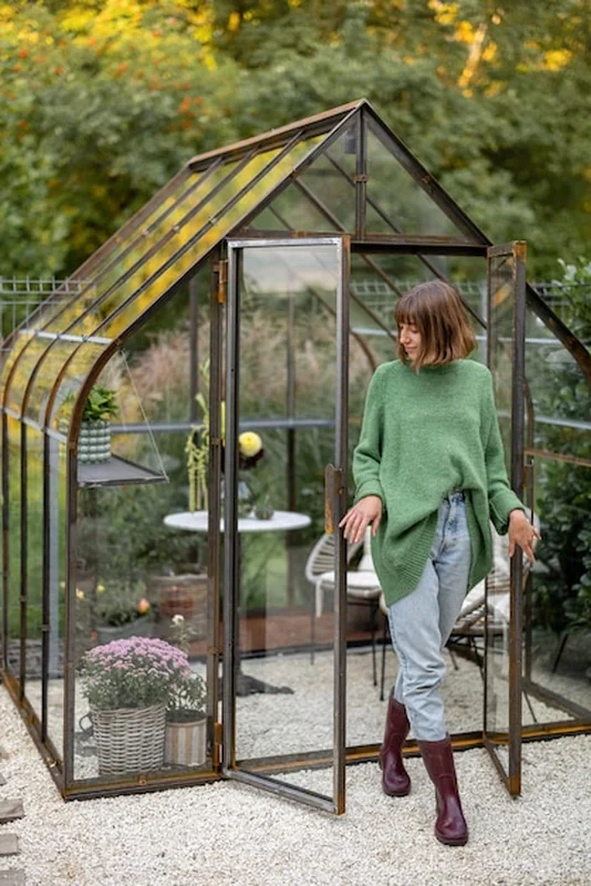 Kobieta jako ogrodnik przy szklarni na podwórku