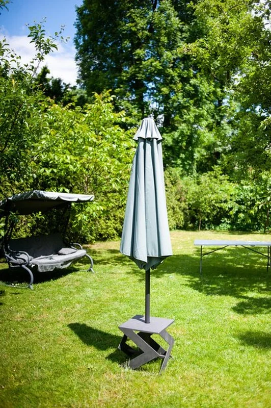 Stół z parasolem na trawniku obok krzeseł