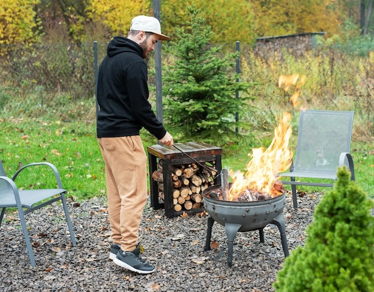 Mężczyzna zapala grilla w przyrodzie obok domu
