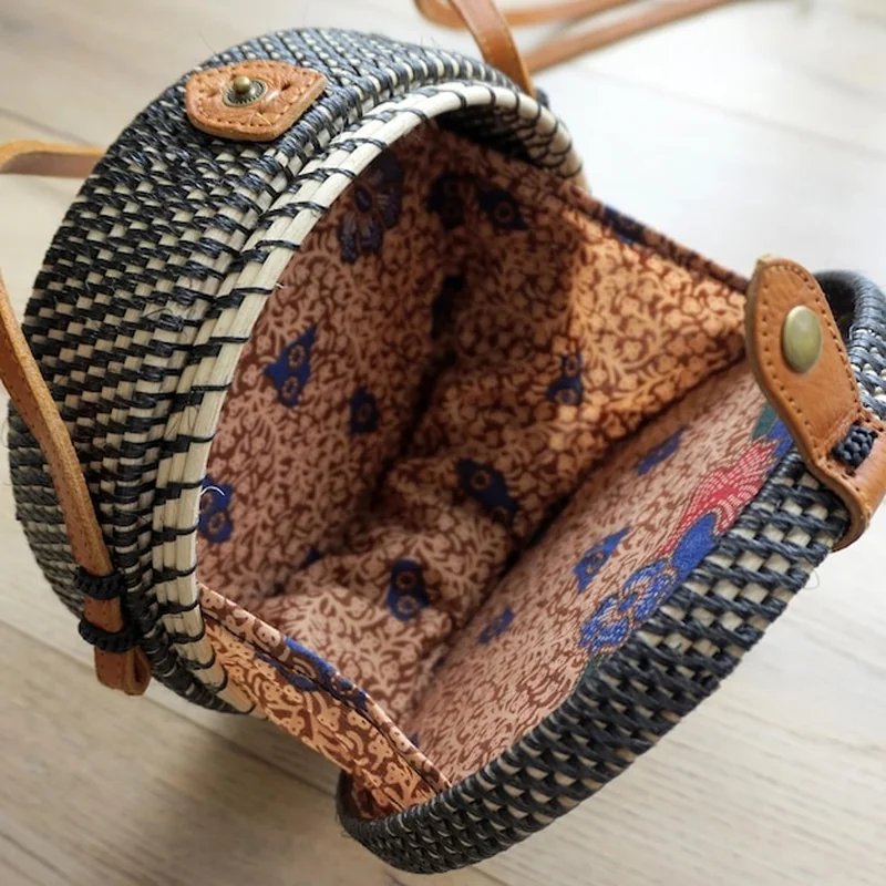 Okrągła otwarta torba z rattanu na drewnianym tle