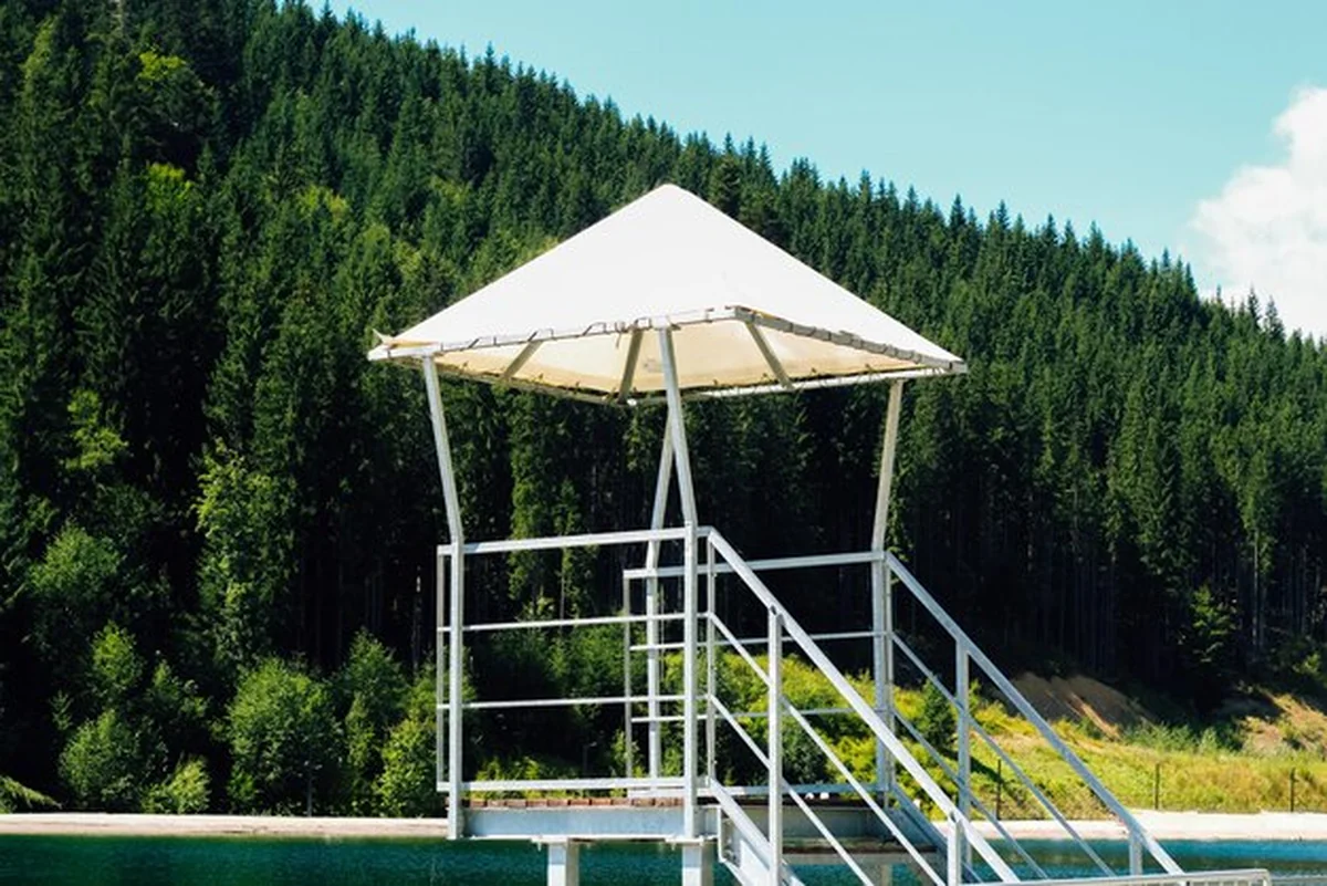 Wieża ratownicza nad spokojnym jeziorem w otoczeniu bujnego lasu