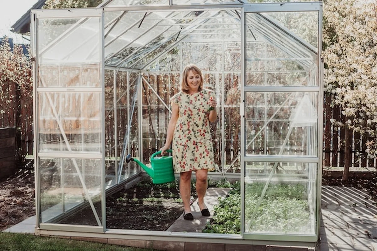 Kobieta podlewa ogród z konewką w szklarni