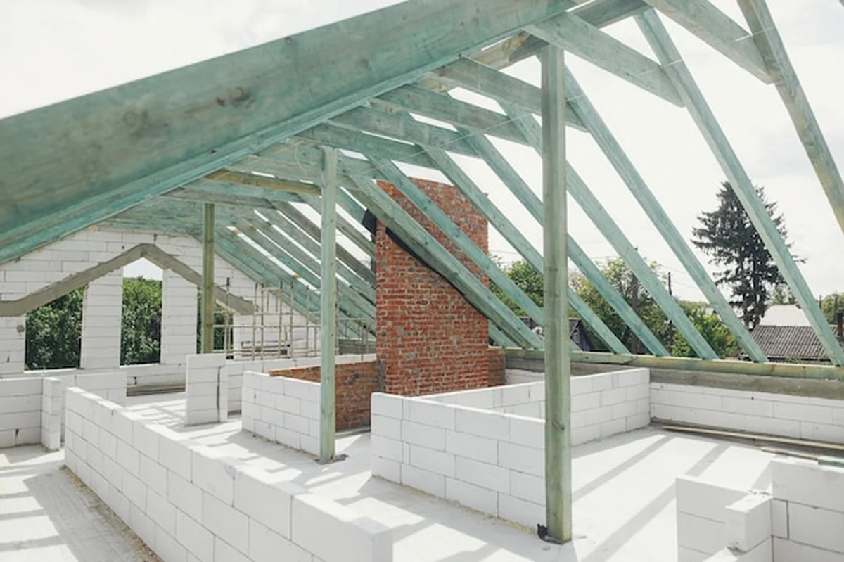 Drewniana więźba dachowa na poddaszu z krokwiami i belkami